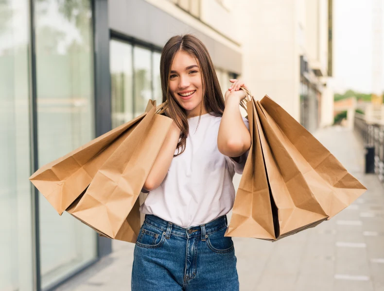 mulher-jovem-e-bonita-segurando-sacolas-de-compras-e-sorrindo-ao-ar-livre